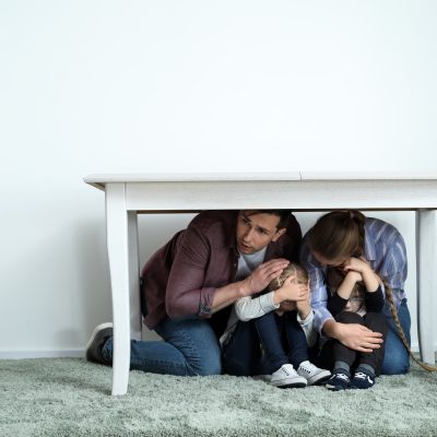 Family under table during earthquake indoors