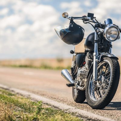 Time to trip. Cropped photo of black vintage motorcycle with helmet on handlebars parking on roadside